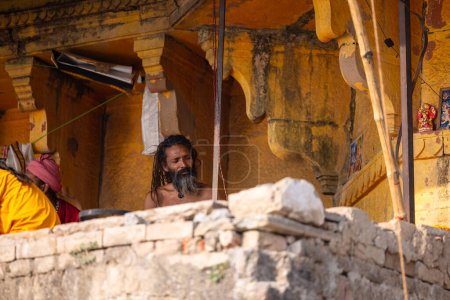 Foto de Varanasi, Uttar Pradesh, India - 05 de marzo de 2023: Retrato del viejo sadhu baba sagrado sentado en ghats cerca de pandillas en varanasi. Kashi es la ciudad más antigua y santa - Imagen libre de derechos