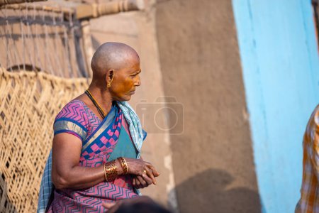 Photo for Varanasi, Uttar Pradesh, India - March 05 2023: Portrait on an old south indian woman with shaved head sitting on stairs at kedar ghat in traditional saree. Bald head is ritual performed in kashi - Royalty Free Image