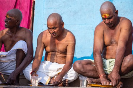 Téléchargez les photos : Varanasi, Uttar Pradesh, Inde - 05 mars 2023 : Portrait d'hommes brahmanes non identifiés du sud de l'Inde exécutant des rituels shraadh sur le ghat de kedar près du fleuve Ganges à varanasi - en image libre de droit