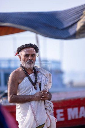 Foto de Varanasi, Uttar Pradesh, India - 05 de marzo de 2023: Retrato de un macho brahmán no identificado que realiza rituales de shraadh en el ghat kedar cerca de las bandas fluviales en varanasi - Imagen libre de derechos