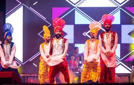 Photo for Bikaner, Rajasthan, India - January 14 2023: Group of young punjabi male artists from punjab performing famous bhangra dance in traditional colourful  at bikaner camel festival - Royalty Free Image
