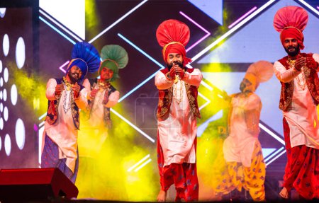 Photo for Bikaner, Rajasthan, India - January 14 2023: Group of young punjabi male artists from punjab performing famous bhangra dance in traditional colourful  at bikaner camel festival - Royalty Free Image