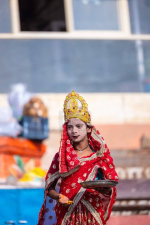 Foto de Varanasi, Uttar Pradesh, India - 05 de marzo de 2023: Retrato de un niño vestido como diosa parvati con la cara pintada de pie cerca de ghat cerca de las pandillas del río para hacer tilak a los turistas - Imagen libre de derechos