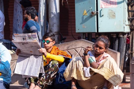 Téléchargez les photos : Varanasi, Uttar Pradesh, Inde - 05 mars 2023 : Un Indien lisant un journal assis sur un banc près du temple Shiv à Varanasi. - en image libre de droit
