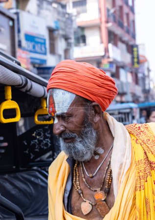 Téléchargez les photos : Varanasi, Uttar Pradesh, Inde - 05 mars 2023 : Portrait de vieux sadhu baba en costume traditionnel marchant sur des ghats près de Ganges à Varanasi. Kashi est la ville la plus ancienne et sainte - en image libre de droit
