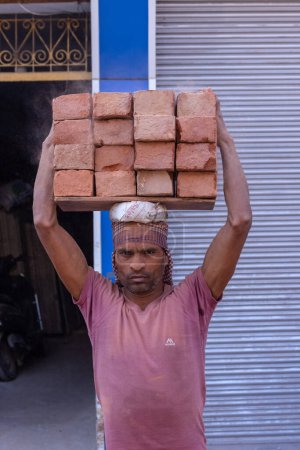 Téléchargez les photos : Varanasi, Uttar Pradesh, Inde - 05 mars 2023 : Rencontré au travail, main-d'œuvre masculine indienne travaillant sur le chantier de construction par la collecte des briques sur sa tête. - en image libre de droit