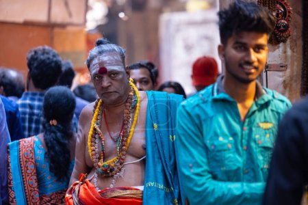 Foto de Varanasi, Uttar Pradesh, India - 05 de marzo de 2023: Retrato de un viejo sadhu baba sagrado con vestimenta tradicional caminando sobre ghats cerca de pandillas en varanasi. Kashi es la ciudad más antigua y santa - Imagen libre de derechos