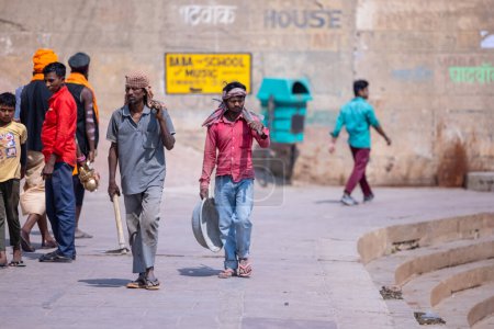 Téléchargez les photos : Varanasi, Uttar Pradesh, Inde - 05 mars 2023 : Rencontre au travail, Groupe de travailleurs indiens marchant sur des ghats près de ganga avec leur équipement sur le chantier de construction - en image libre de droit