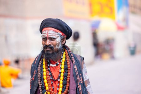 Téléchargez les photos : Varanasi, Uttar Pradesh, Inde - 05 mars 2023 : Portrait du saint sadhu baba en costume traditionnel marchant sur les ghats près des Ganges à Varanasi. Kashi est la ville la plus ancienne et sainte - en image libre de droit