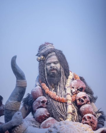 Téléchargez les photos : Masan Holi, Portrait d'un artiste masculin agir comme seigneur shiv avec des cendres sèches sur le visage et le corps aussi dans l'air tout en célébrant le festival holi comme tradition à Harishchandra ghat à varanasi, Inde. - en image libre de droit