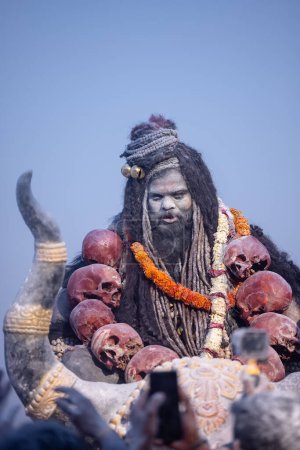 Téléchargez les photos : Masan Holi, Portrait d'un artiste masculin agir comme seigneur shiv avec des cendres sèches sur le visage et le corps aussi dans l'air tout en célébrant le festival holi comme tradition à Harishchandra ghat à varanasi, Inde. - en image libre de droit