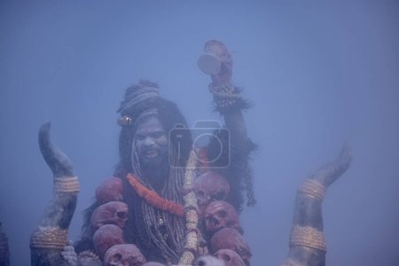 Masan Holi, Portrait of an male artist act as lord shiv with dry ash on face and body also in air while celebrating the holi festival as tradition at Harishchandra ghat in varanasi, India.