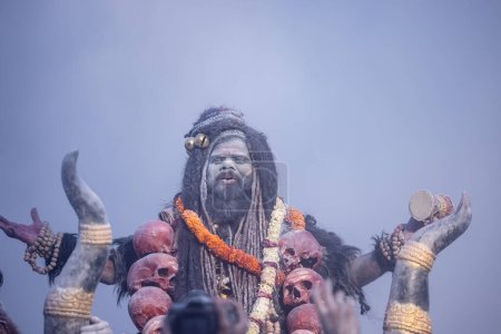 Foto de Masan Holi, Retrato de un artista masculino actuar como señor shiv con ceniza seca en la cara y el cuerpo también en el aire mientras se celebra el festival de holi como tradición en Harishchandra ghat en varanasi, India. - Imagen libre de derechos