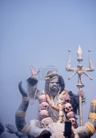 Masan Holi, Retrato de un artista masculino actuar como señor shiv con ceniza seca en la cara y el cuerpo también en el aire mientras se celebra el festival de holi como tradición en Harishchandra ghat en varanasi, India.