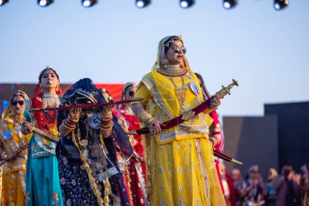 Foto de Bikaner, Rajastán, India - 14 de enero de 2023: Retrato de mujeres indias hermosas jóvenes en vestido de rajasthani lehenga choli étnico que participan en el desfile de moda Miss Marwar durante el festival de camellos de ciclista - Imagen libre de derechos
