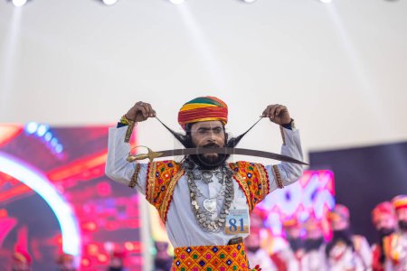 Foto de Bikaner, Rajastán, India - 14 de enero de 2023: Retrato de un hombre rajasthani rajput con barba y bigote con vestido blanco tradicional rajasthani, joyas y turbante en el festival de camellos bikaner. - Imagen libre de derechos