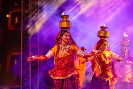 Photo for Pushkar, Rajasthan, India - November 05, 2022: An female artists performing rajasthani folk dance Ghoomar in traditional colorful dresses and metal pots with fire in Pushkar fair. Selective focus. - Royalty Free Image