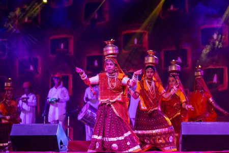 Téléchargez les photos : Pushkar, Rajasthan, Inde - 05 novembre 2022 : Une artiste féminine exécutant la danse folklorique rajasthani Ghoomar dans des robes colorées traditionnelles et des pots en métal avec feu à la foire de Pushkar. Concentration sélective. - en image libre de droit