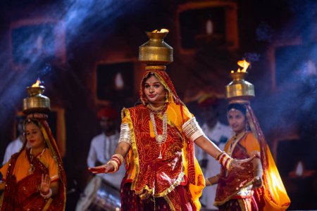 Photo for Pushkar, Rajasthan, India - November 05, 2022: An female artists performing rajasthani folk dance Ghoomar in traditional colorful dresses and metal pots with fire in Pushkar fair. Selective focus. - Royalty Free Image