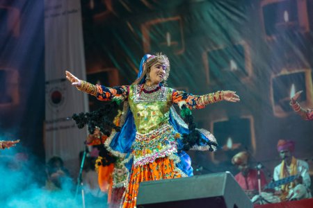 Foto de Pushkar, Rajastán, India - 06 de noviembre 2022: Artista femenina que realiza danza folclórica rajasthani en el escenario en la feria pushkar en colorido vestido étnico rajasthani y joyas. - Imagen libre de derechos