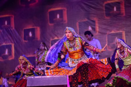 Téléchargez les photos : Pushkar, Rajasthan, Inde - 06 novembre 2022 : Une artiste féminine exécute une danse folklorique rajasthani sur scène à la foire pushkar dans une robe et des bijoux ethniques rajasthani colorés. - en image libre de droit
