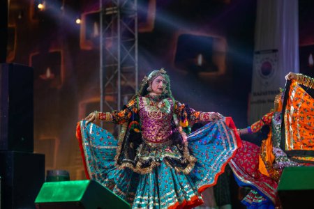 Foto de Pushkar, Rajastán, India - 06 de noviembre 2022: Artista femenina que realiza danza folclórica rajasthani en el escenario en la feria pushkar en colorido vestido étnico rajasthani y joyas. - Imagen libre de derechos