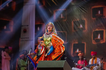 Téléchargez les photos : Pushkar, Rajasthan, Inde - 06 novembre 2022 : Une artiste féminine exécute une danse folklorique rajasthani sur scène à la foire pushkar dans une robe et des bijoux ethniques rajasthani colorés. - en image libre de droit