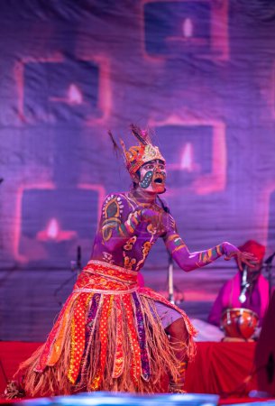Photo for Pushkar, Rajasthan, India - November 06 2022: Indian male artist performing rajasthani folk dance Sahariya tribe with painted face and colorful paint on body with ethnic dress at fair. - Royalty Free Image
