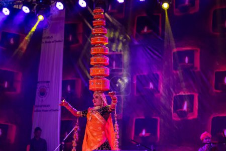 Foto de Pushkar, Rajastán, India - 06 de noviembre 2022: Artista realizando danza folclórica rajasthani en el escenario en la feria pushkar en colorido vestido y joyas rajasthani étnicos. - Imagen libre de derechos
