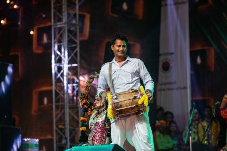 Téléchargez les photos : Pushkar, Rajasthan, Inde - 06 novembre 2022 : Portrait d'un jeune artiste masculin jouant de la danse folklorique rajasthani sur scène à la foire pushkar en robe rajasthani ethnique colorée. - en image libre de droit