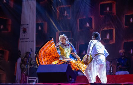 Foto de Pushkar, Rajastán, India - 06 de noviembre 2022: Artista realizando danza folclórica rajasthani en el escenario en la feria pushkar en colorido vestido y joyas rajasthani étnicos. - Imagen libre de derechos
