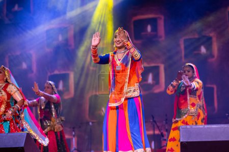 Foto de Pushkar, Rajastán, India - 06 de noviembre 2022: Hermosas artistas femeninas que realizan danza folclórica rajasthani en el escenario en la feria pushkar con coloridos vestidos y joyas étnicas rajasthani. - Imagen libre de derechos