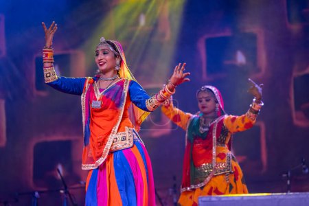 Foto de Pushkar, Rajastán, India - 06 de noviembre 2022: Hermosas artistas femeninas que realizan danza folclórica rajasthani en el escenario en la feria pushkar con coloridos vestidos y joyas étnicas rajasthani. - Imagen libre de derechos