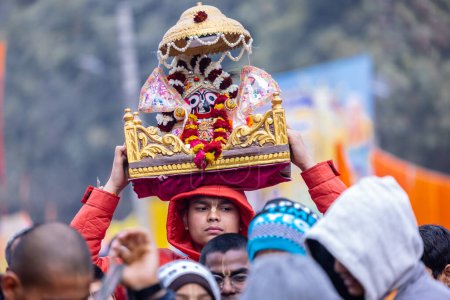 Téléchargez les photos : Ghaziabad, Uttar Pradesh, Inde - 28 janvier 2024 : Portrait d'un prêtre tenant l'idole du seigneur jagannath sur sa tête pendant le yatra de la rath. - en image libre de droit