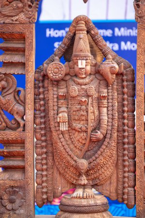 Téléchargez les photos : Art en bois, idole en bois faite à la main sur lord tirupati à surajkund foire de l'artisanat. Concentration sélective. - en image libre de droit