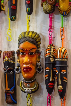 Handmade colorful tribal look face mask souvenir hanging on plain background. Selective focus on object.