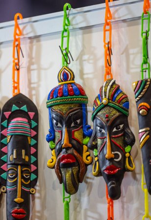 Foto de Handmade colorful tribal look face mask souvenir hanging on plain background. Selective focus on object. - Imagen libre de derechos