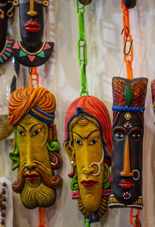 Handgemachtes farbenfrohes Gesichtsmasken-Souvenir im Stammeslook, das auf schlichtem Hintergrund hängt. Selektiver Fokus auf Objekt.