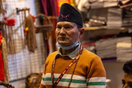 Téléchargez les photos : New Delhi, Inde - 18 Novembre 2023 : Portrait d'un vendeur masculin de nepal en tenue traditionnelle à un comptoir dans le salon delhi pour vendre leurs produits. - en image libre de droit