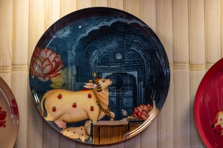 Nueva Delhi, India - 18 de noviembre de 2023: Pintura hecha a mano de vaca santa en placa de cerámica colgada en la pared.
