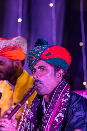 Foto de Bikaner, Rajastán, India - 13 de enero de 2023: Festival de camellos, Retrato de un artista masculino rajastaní actuando en el escenario durante el festival de camellos en bikaner con vestido tradicional rajastaní y turbante colorido. - Imagen libre de derechos