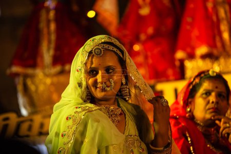 Téléchargez les photos : Bikaner, Rajasthan, Inde - 13 janvier 2023 : Groupe de belles femmes de bikaner vêtues de vêtements rajashani colorés traditionnels et jouant du gangaure culturel pooja sur scène pendant le festival du chameau. - en image libre de droit