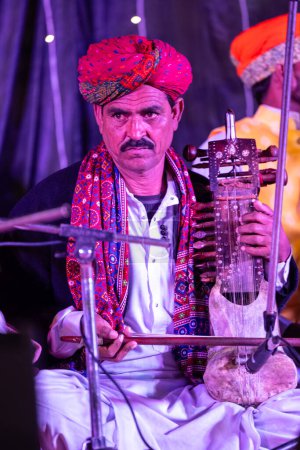 Photo for Bikaner, Rajasthan, India - January 13 2023: Camel Festival, Portrait of rajasthani male artist performing on stage during bikaner camel festival in traditional rajasthani dress and colourful turban. - Royalty Free Image