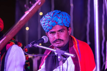 Photo for Bikaner, Rajasthan, India - January 13 2023: Camel Festival, Portrait of rajasthani male artist performing on stage during bikaner camel festival in traditional rajasthani dress and colourful turban. - Royalty Free Image