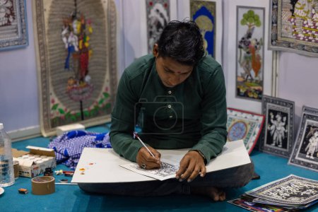 Téléchargez les photos : New Delhi, Inde - 18 novembre 2023 : Portrait d'un artiste folklorique indien peint sur toile lors d'une foire commerciale. - en image libre de droit