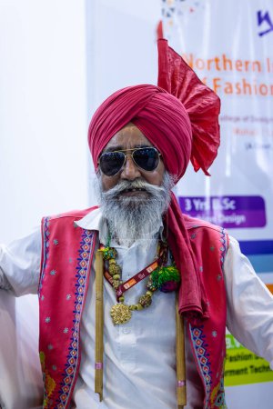 Foto de Nueva Delhi, India - 18 de noviembre de 2023: Retrato de un artista indio de bhangra popular sardar que mira a la cámara mientras está vestido con ropa tradicional para participar en la feria. - Imagen libre de derechos