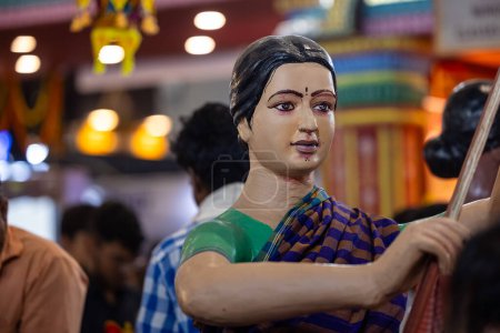 Téléchargez les photos : New Delhi, Inde - 18 novembre 2023 : Statue faite à la main de la femme indienne dans un saree traditionnel exposé à la foire exécutant des travaux ménagers. - en image libre de droit