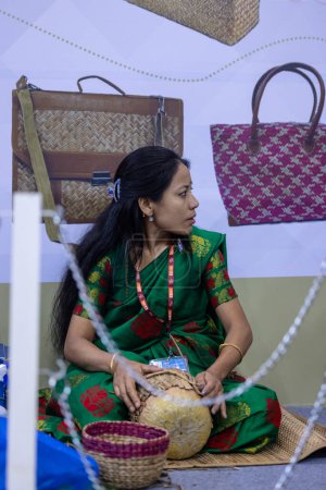 Téléchargez les photos : New Delhi, Inde - 18 novembre 2023 : Portrait d'une artiste folklorique indienne peignant sur toile lors d'une foire commerciale. - en image libre de droit