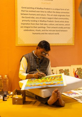 Téléchargez les photos : New Delhi, Inde - 18 novembre 2023 : Portrait d'un artiste folklorique indien peint sur toile lors d'une foire commerciale. - en image libre de droit