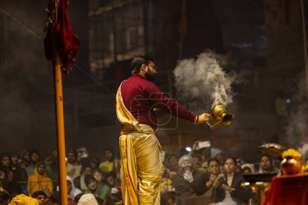 Photo for Varanasi, Uttar Pradesh, India - January 18 2024: Ganga aarti, Portrait of young male priest performing holy river ganges evening aarti at dashashwamedh ghat in traditional dress with hindu rituals. - Royalty Free Image